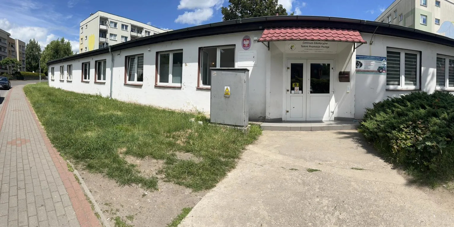Parterowy biały budynek szkoły przy ul. Cukrowniczej 2 w Gryficach, wejście pod czerwonym daszkiem