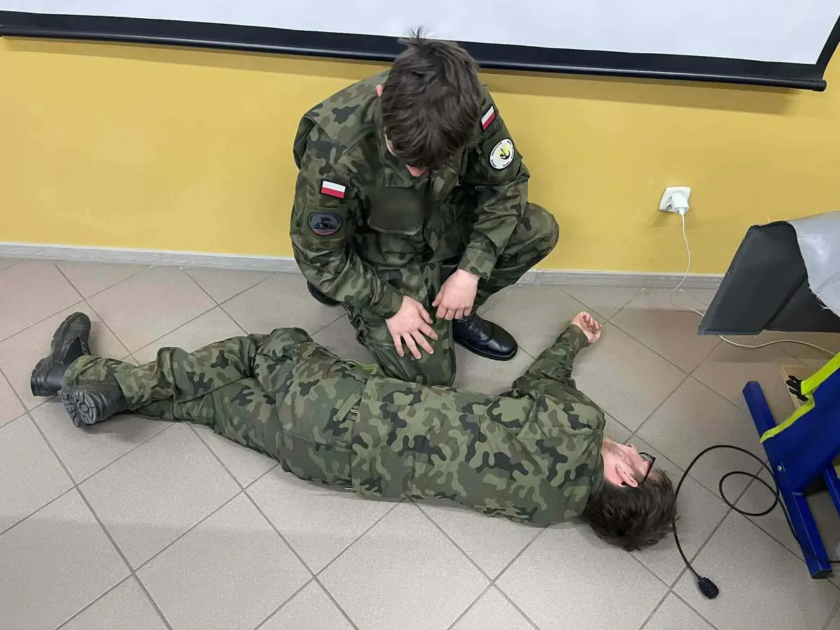 Kadet ćwiczy udzielanie pierwszej pomocy koledze leżącemu na podłodze